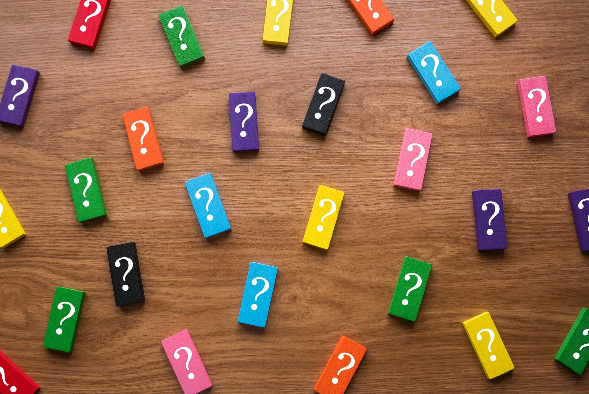 A colorful wooden block with a symbol of question on wooden background.